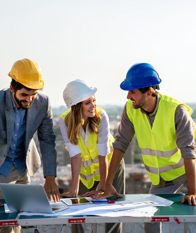 Business, building, teamwork and people concept. Group of engineers and architects in hardhats with blueprint on construction site