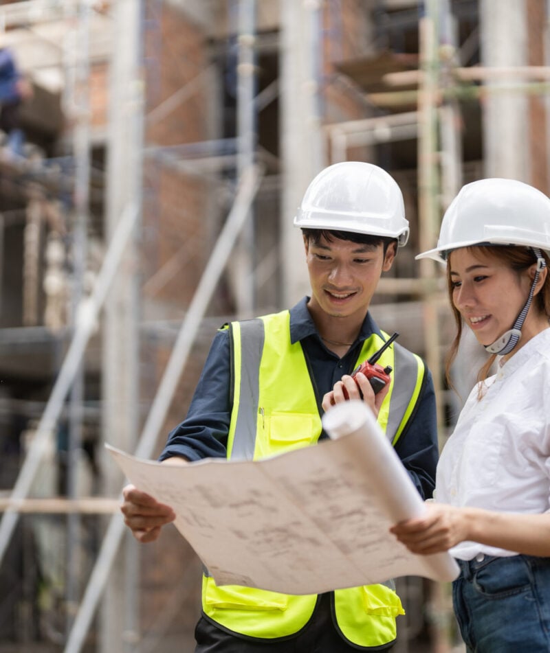 engineering and construction managers discussing project blue print on the table at construction site.