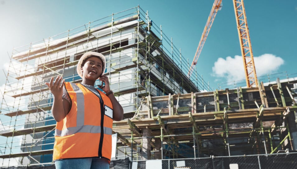 Shot of a young woman using a smartphone while working at a construction site.